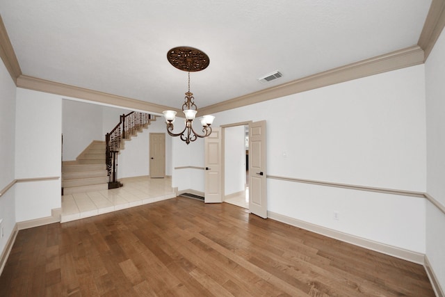 interior space featuring hardwood / wood-style flooring, ornamental molding, and an inviting chandelier