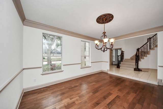 unfurnished dining area with hardwood / wood-style flooring, ornamental molding, and an inviting chandelier