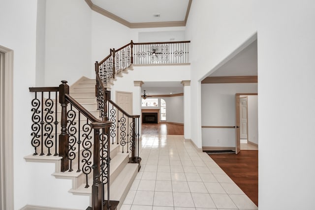 entrance foyer featuring ceiling fan, light tile patterned flooring, a high ceiling, and ornamental molding