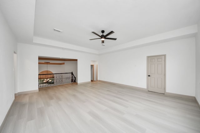 unfurnished living room featuring ceiling fan, a tray ceiling, and light wood-type flooring