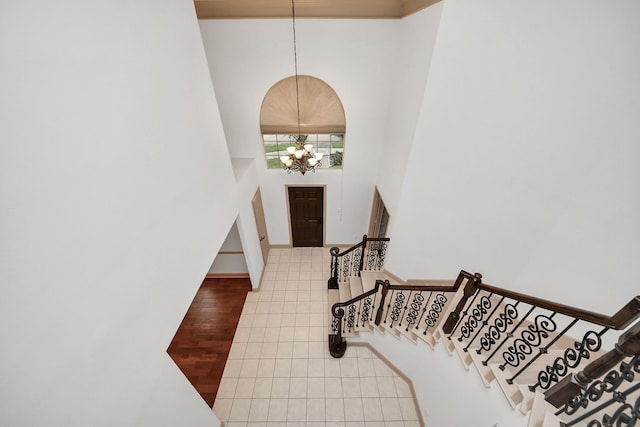 tiled entrance foyer with a towering ceiling and a notable chandelier