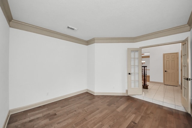 spare room featuring a textured ceiling, crown molding, french doors, and light wood-type flooring