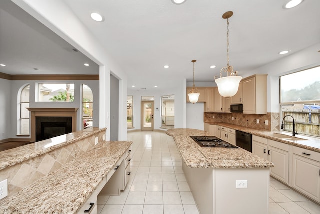 kitchen with sink, a kitchen island, pendant lighting, light stone counters, and black appliances