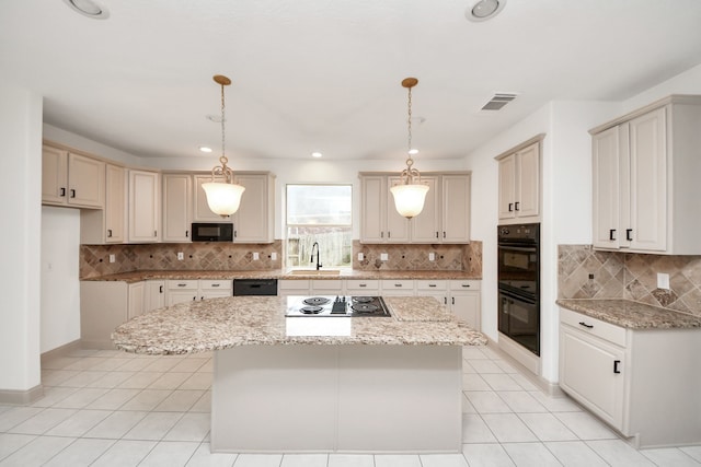 kitchen featuring black appliances, light stone countertops, pendant lighting, and a center island