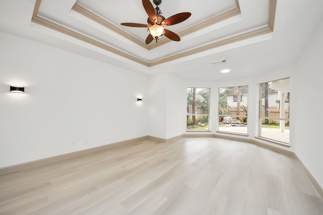 spare room featuring light wood-type flooring, ceiling fan, and a tray ceiling