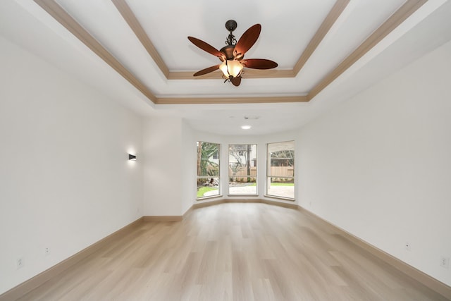 unfurnished living room featuring ceiling fan, a tray ceiling, ornamental molding, and light wood-type flooring