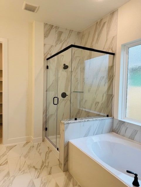 bathroom featuring a wealth of natural light and shower with separate bathtub