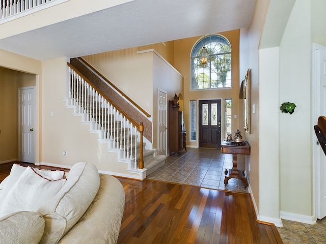 entryway with a towering ceiling and dark wood-type flooring