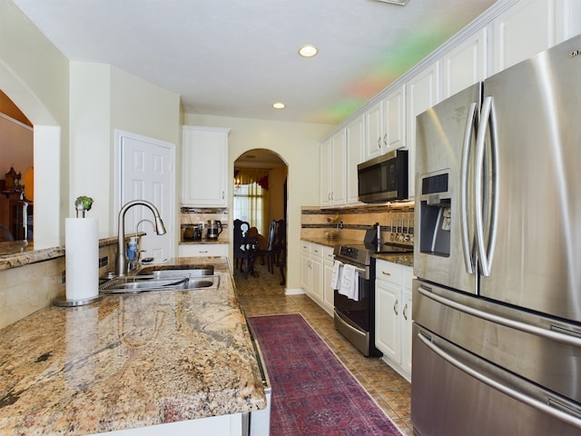 kitchen with light stone counters, sink, white cabinetry, and appliances with stainless steel finishes