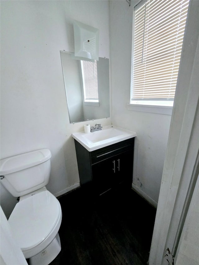 bathroom with wood finished floors, vanity, toilet, and baseboards