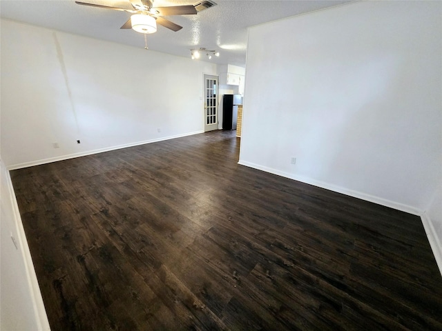 unfurnished room with ceiling fan, dark wood-style flooring, a textured ceiling, and baseboards