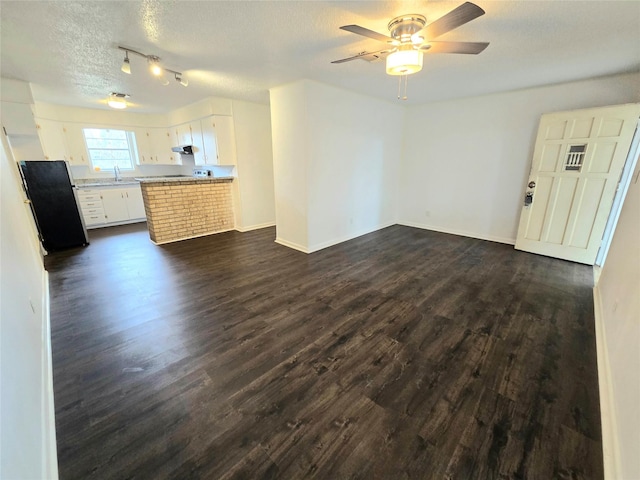 unfurnished living room with a textured ceiling, ceiling fan, a sink, and dark wood finished floors