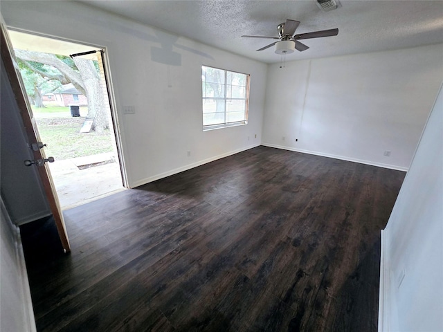 empty room with a textured ceiling, dark wood-style floors, and baseboards