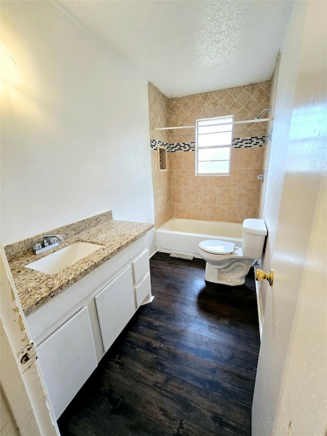 bathroom with a textured ceiling, shower / bathtub combination, toilet, wood finished floors, and vanity