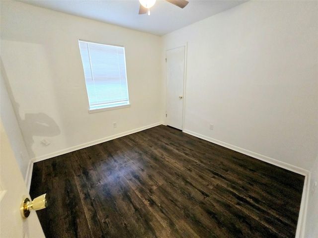 empty room featuring dark wood-style floors, a ceiling fan, and baseboards