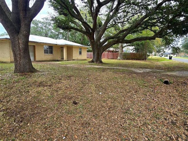 view of yard with an attached garage and fence