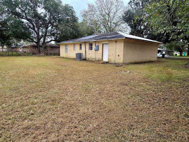 back of property with central air condition unit, a yard, and brick siding