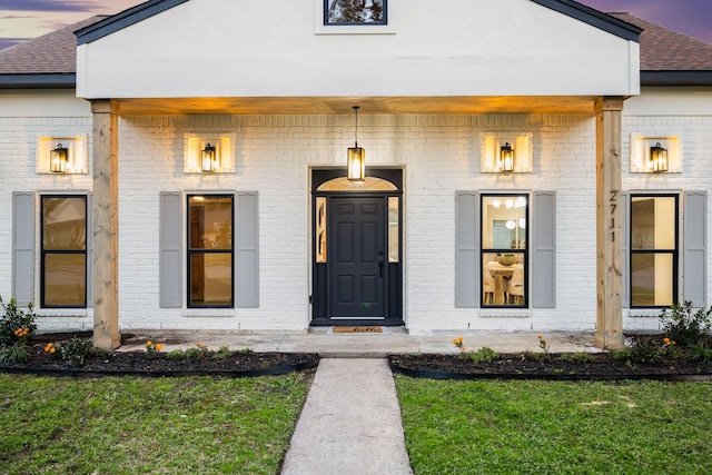 exterior entry at dusk featuring a yard