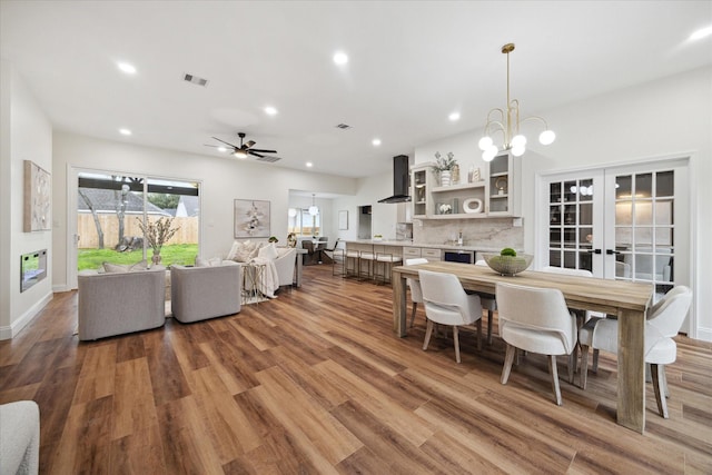 dining area featuring french doors, ceiling fan with notable chandelier, and wood-type flooring