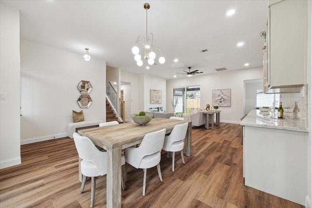 dining room featuring ceiling fan with notable chandelier and light hardwood / wood-style floors