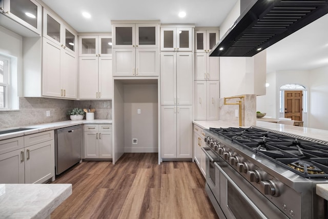 kitchen featuring white cabinets, dark hardwood / wood-style floors, wall chimney range hood, and stainless steel appliances