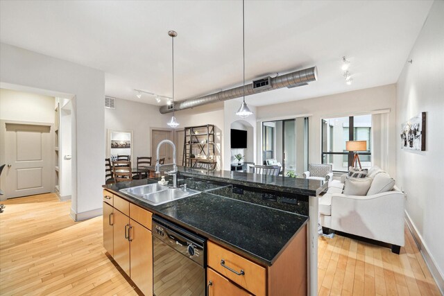 kitchen with light wood-type flooring, sink, an island with sink, and black dishwasher