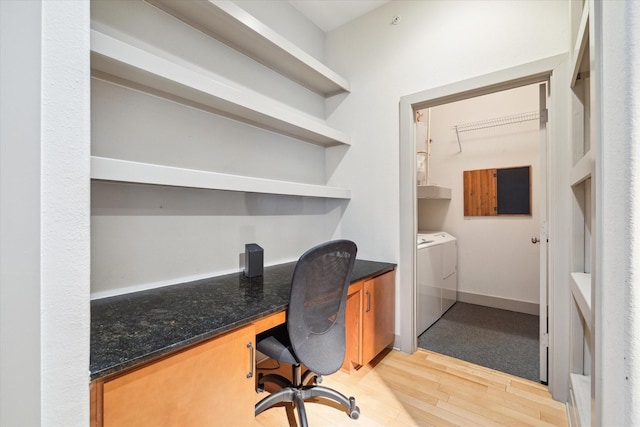 office space with built in desk, washing machine and clothes dryer, and light wood-type flooring