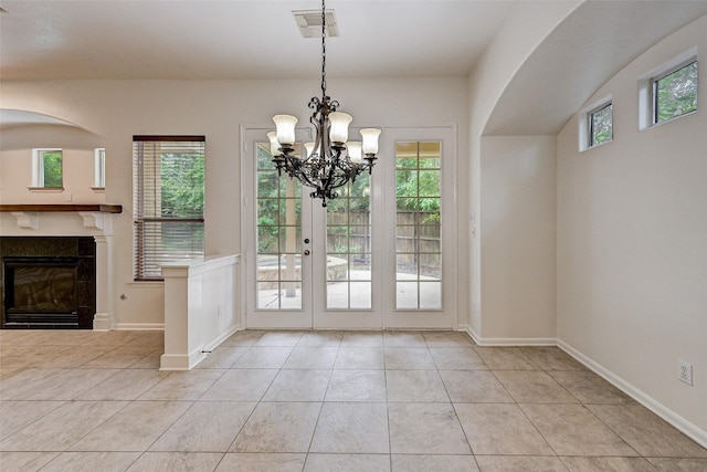 doorway to outside featuring french doors, light tile patterned floors, plenty of natural light, and a tiled fireplace