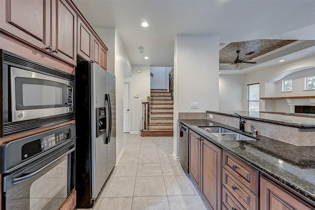 kitchen with ceiling fan, dark stone countertops, black appliances, sink, and light tile patterned floors