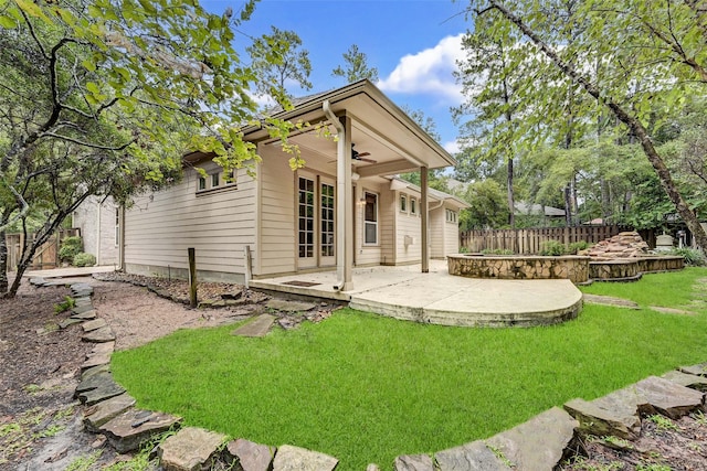 rear view of house featuring ceiling fan, a lawn, and a patio