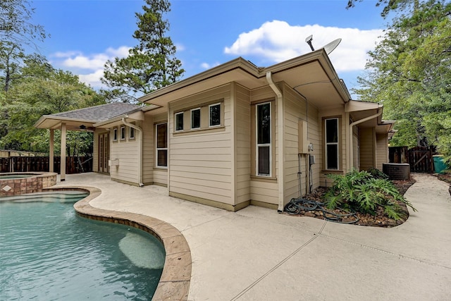 exterior space featuring a swimming pool with hot tub, cooling unit, and a patio area