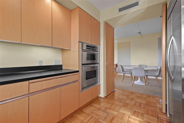 kitchen featuring light parquet flooring, light brown cabinetry, and appliances with stainless steel finishes