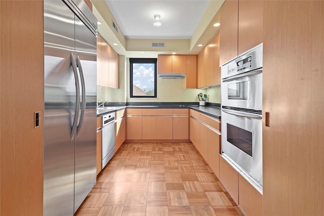 kitchen featuring extractor fan, appliances with stainless steel finishes, light brown cabinets, light parquet flooring, and sink