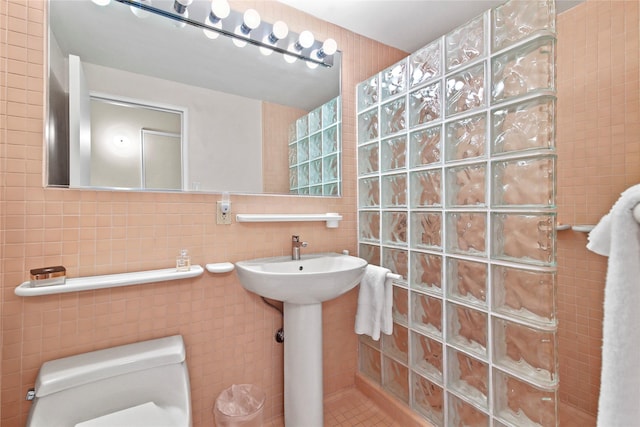 bathroom with tile walls, tile patterned floors, walk in shower, and toilet