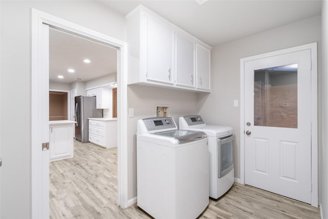 laundry room featuring cabinets, light hardwood / wood-style floors, and washer and clothes dryer