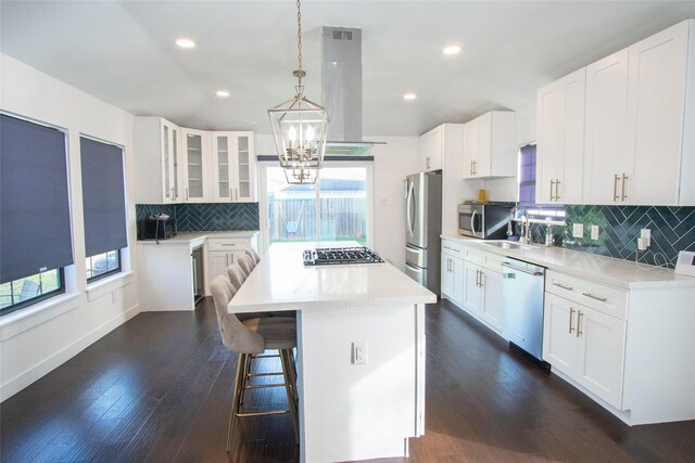 kitchen featuring island exhaust hood, white cabinetry, stainless steel appliances, and a kitchen island