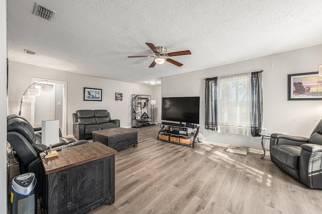 living room with hardwood / wood-style flooring, a textured ceiling, and ceiling fan