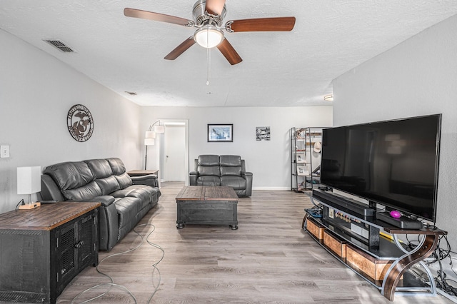 living room with ceiling fan, hardwood / wood-style floors, and a textured ceiling