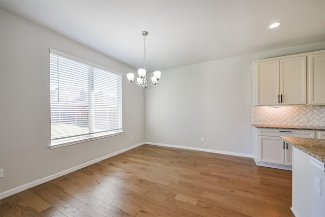 unfurnished dining area with a chandelier and light hardwood / wood-style floors