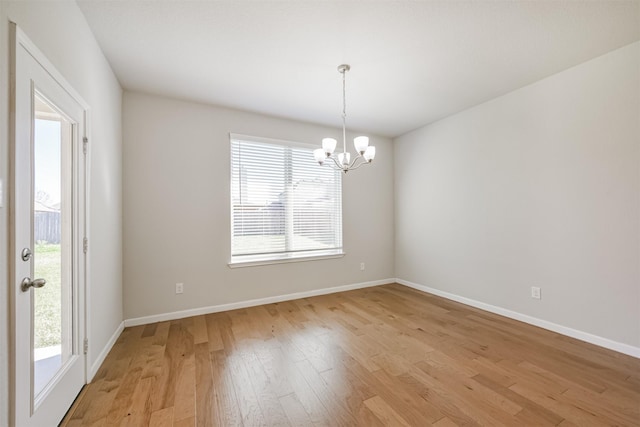 spare room with a notable chandelier and light hardwood / wood-style floors