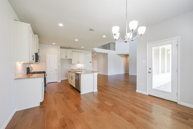 kitchen featuring decorative light fixtures, sink, white cabinets, a kitchen island with sink, and stainless steel appliances