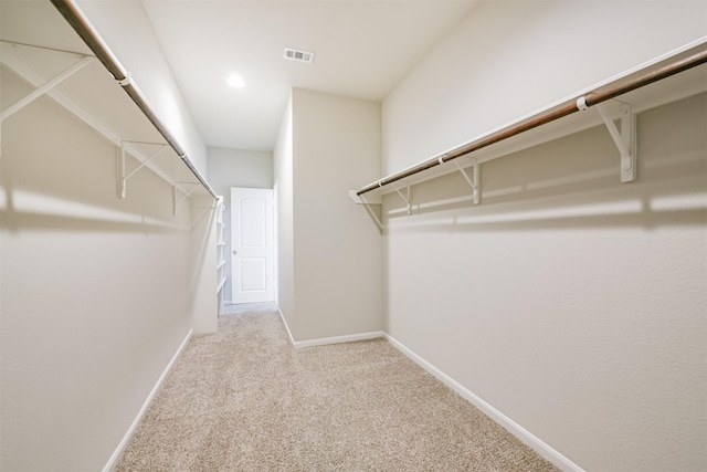 walk in closet with light colored carpet