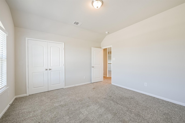 unfurnished bedroom with lofted ceiling, multiple windows, and carpet flooring