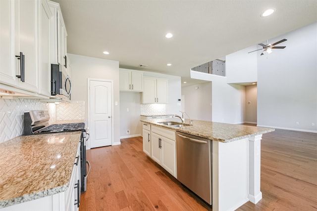 kitchen featuring appliances with stainless steel finishes, sink, a center island with sink, and white cabinets