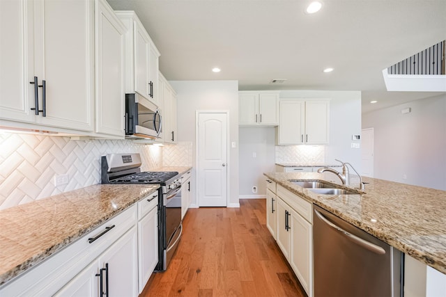 kitchen with sink, light hardwood / wood-style flooring, appliances with stainless steel finishes, white cabinetry, and light stone counters