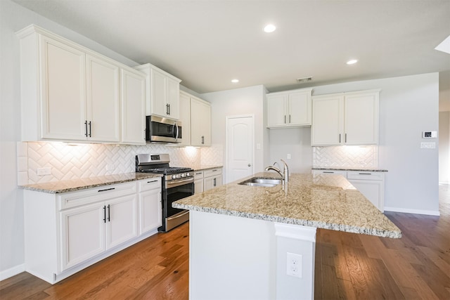 kitchen featuring appliances with stainless steel finishes, a kitchen island with sink, white cabinets, and light stone counters