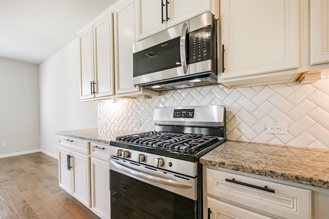 kitchen with light stone counters, decorative backsplash, light hardwood / wood-style floors, and appliances with stainless steel finishes