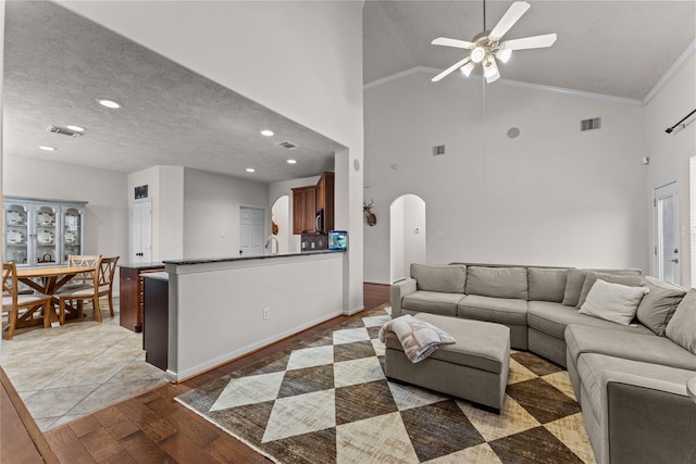 living room featuring ceiling fan, light hardwood / wood-style flooring, crown molding, and vaulted ceiling