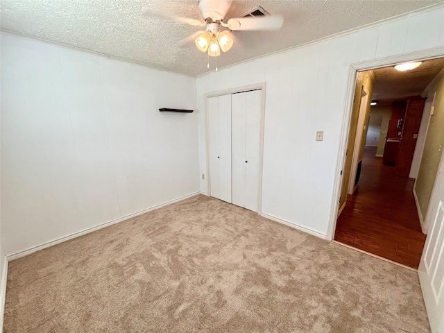 unfurnished bedroom with ceiling fan, a closet, light carpet, and a textured ceiling