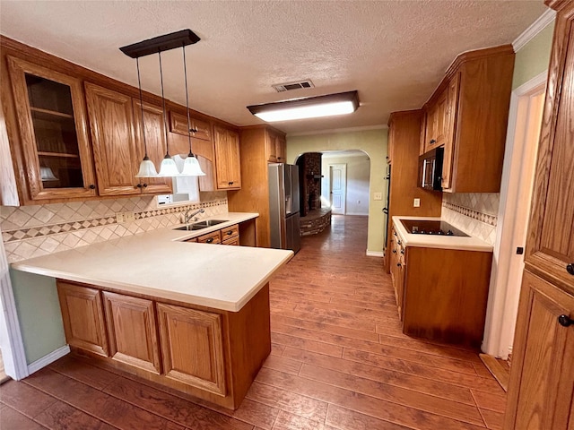 kitchen with pendant lighting, kitchen peninsula, sink, a textured ceiling, and stainless steel fridge